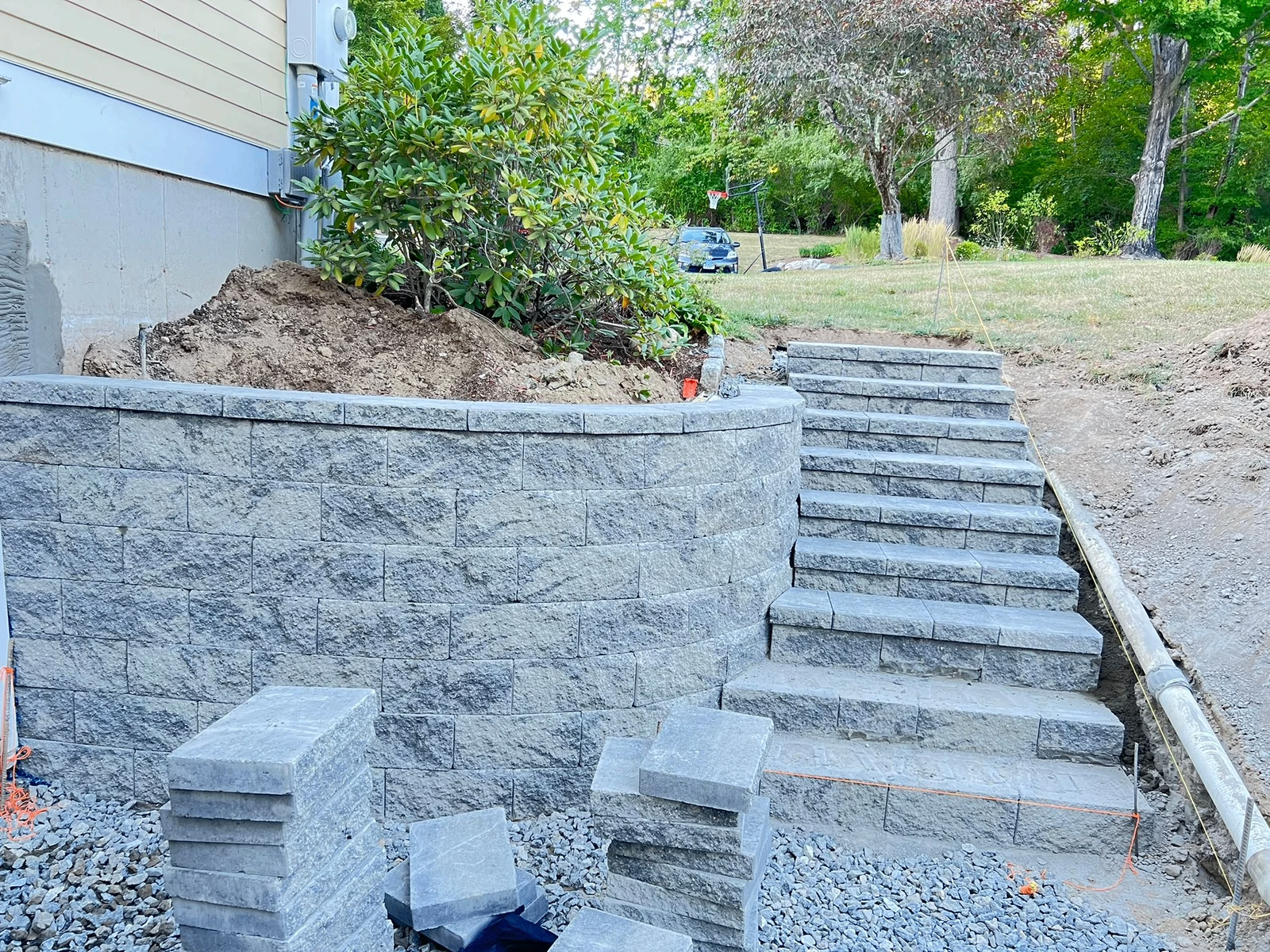 Curved retaining wall with stone staircase on a sloped yard